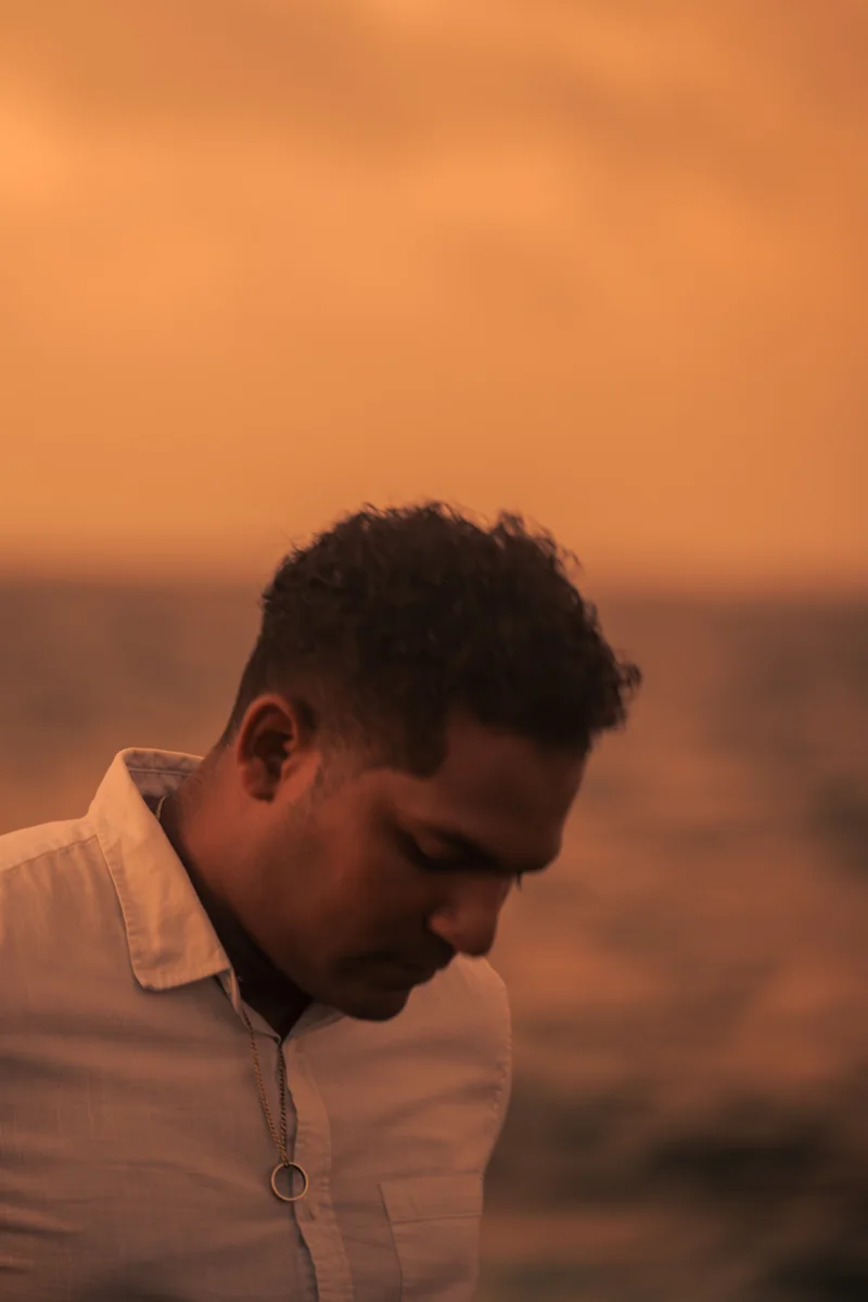 Adrián Ch junto al mar al atardecer